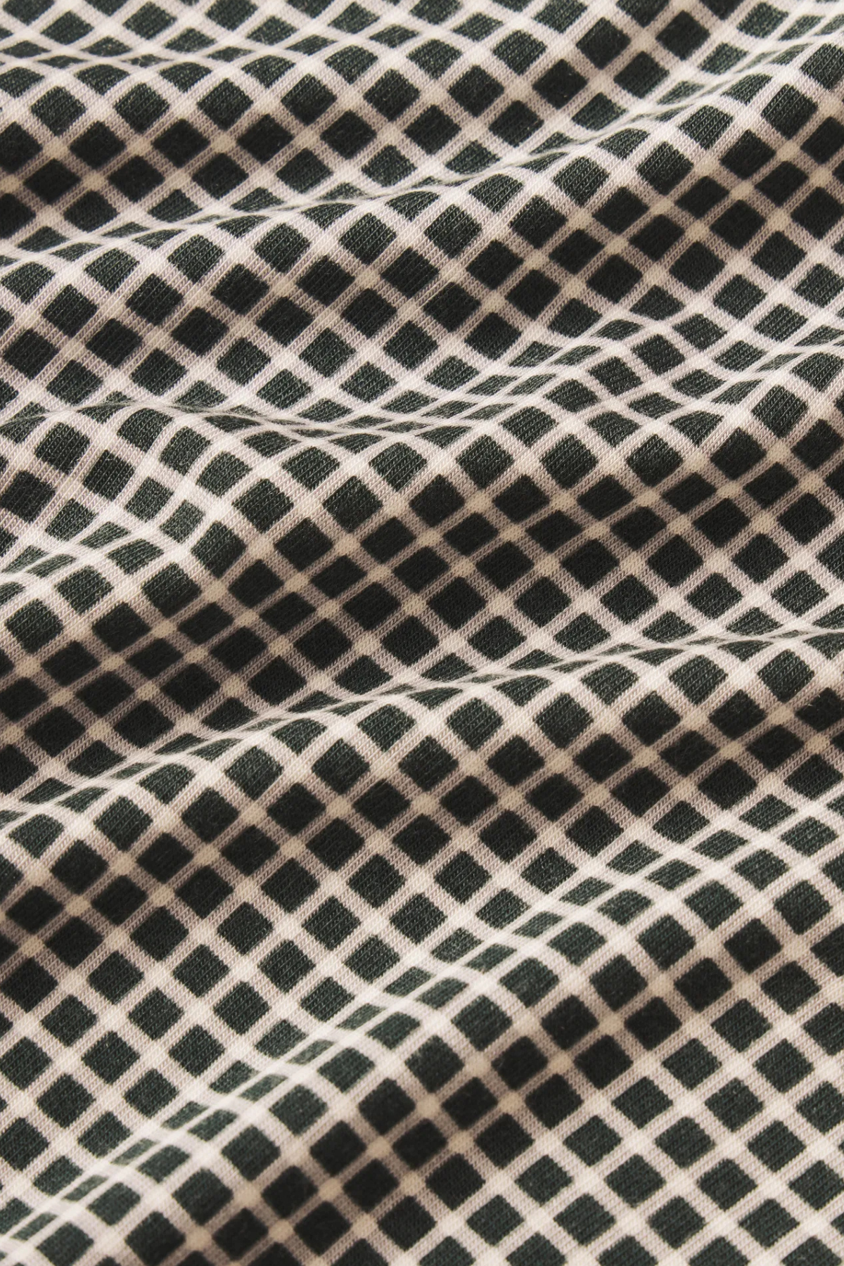 A close-up of a black and beige checkered fabric with a fine knit texture and soft folds.